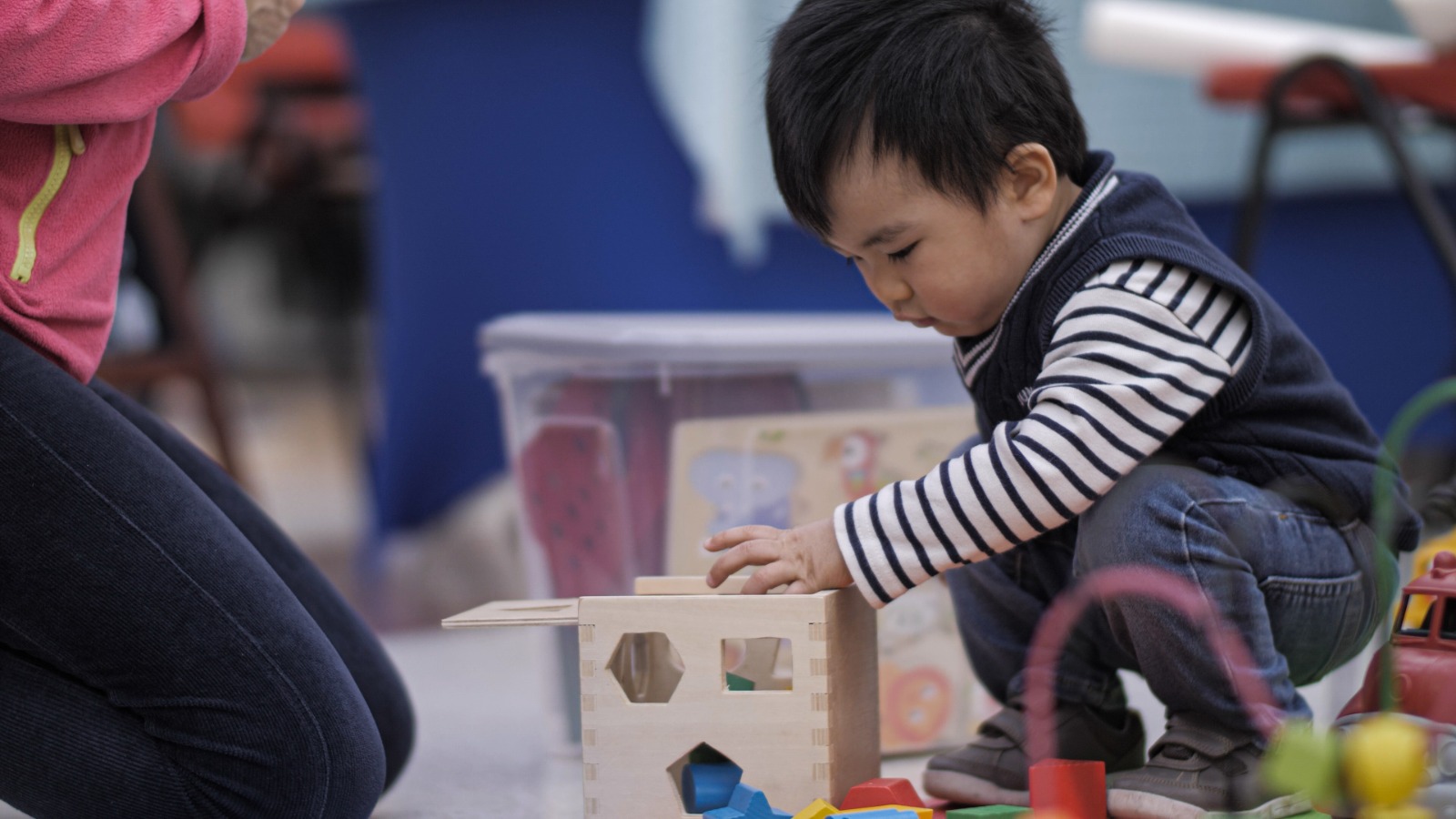 Child playing with a shape based toy on the floor
