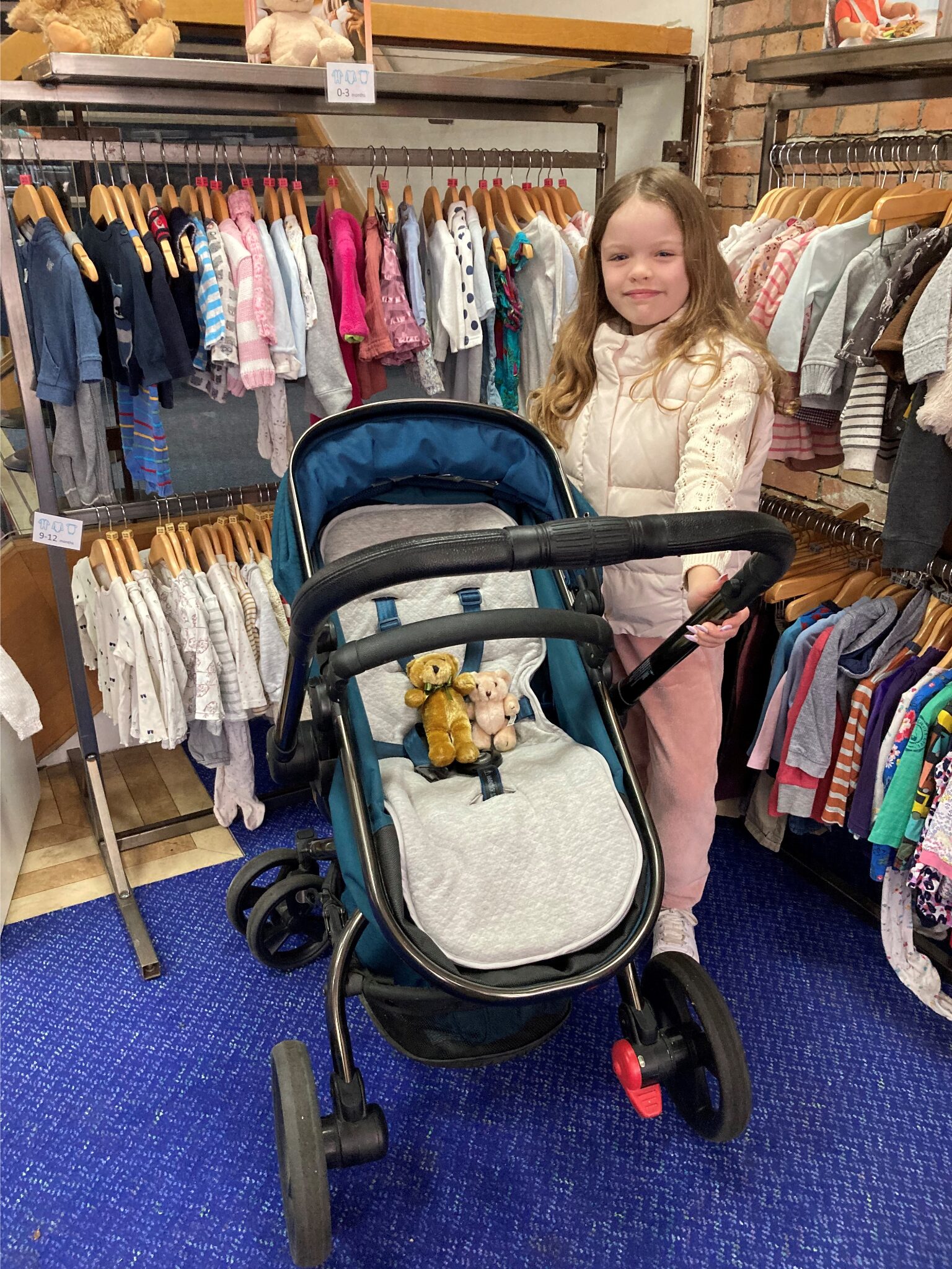 Child with buggy infront of lots of small children's clothes