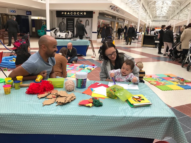Josh in shopping centre at table with child drawing