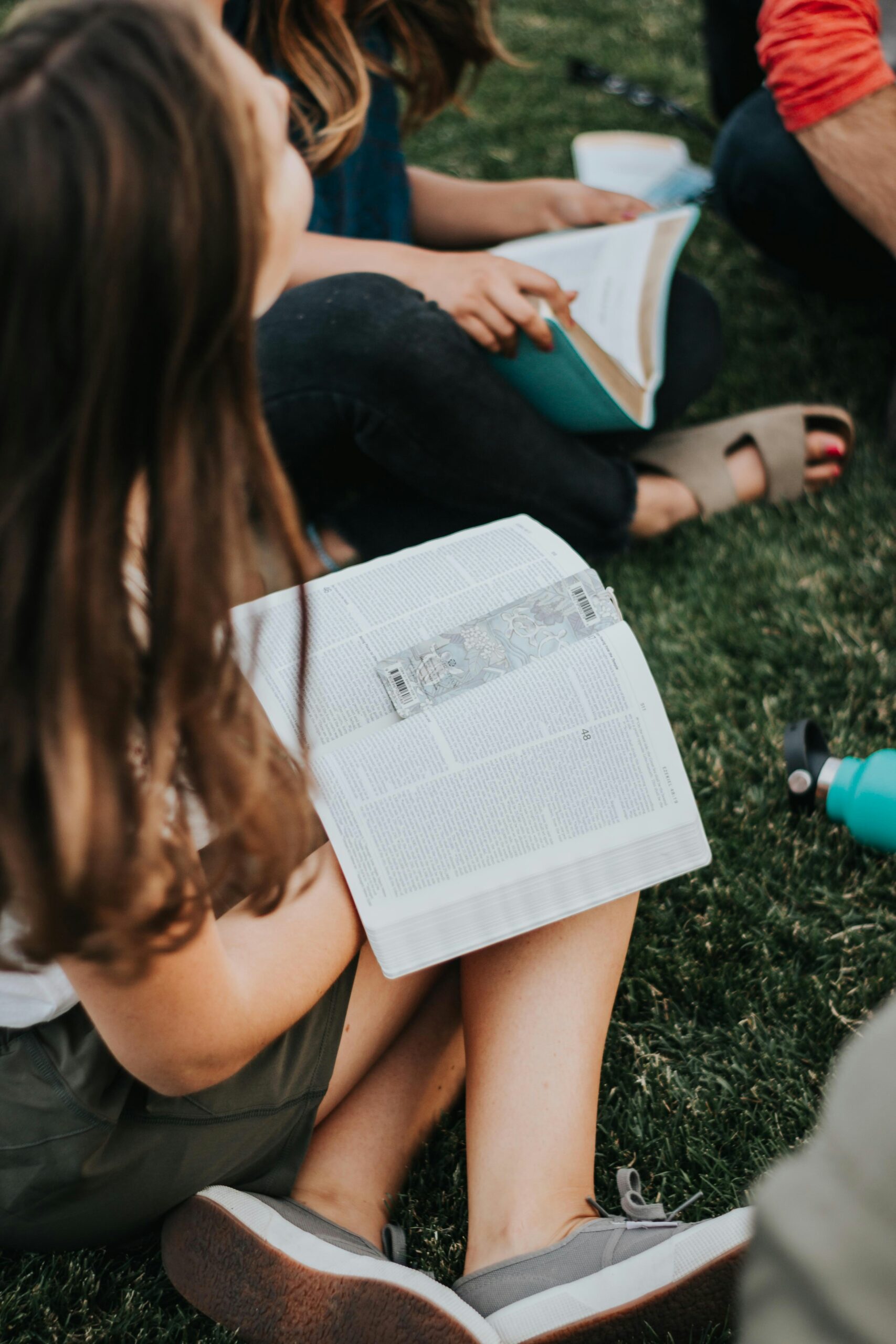 Child on the grass with a book open with a bookmark in it
