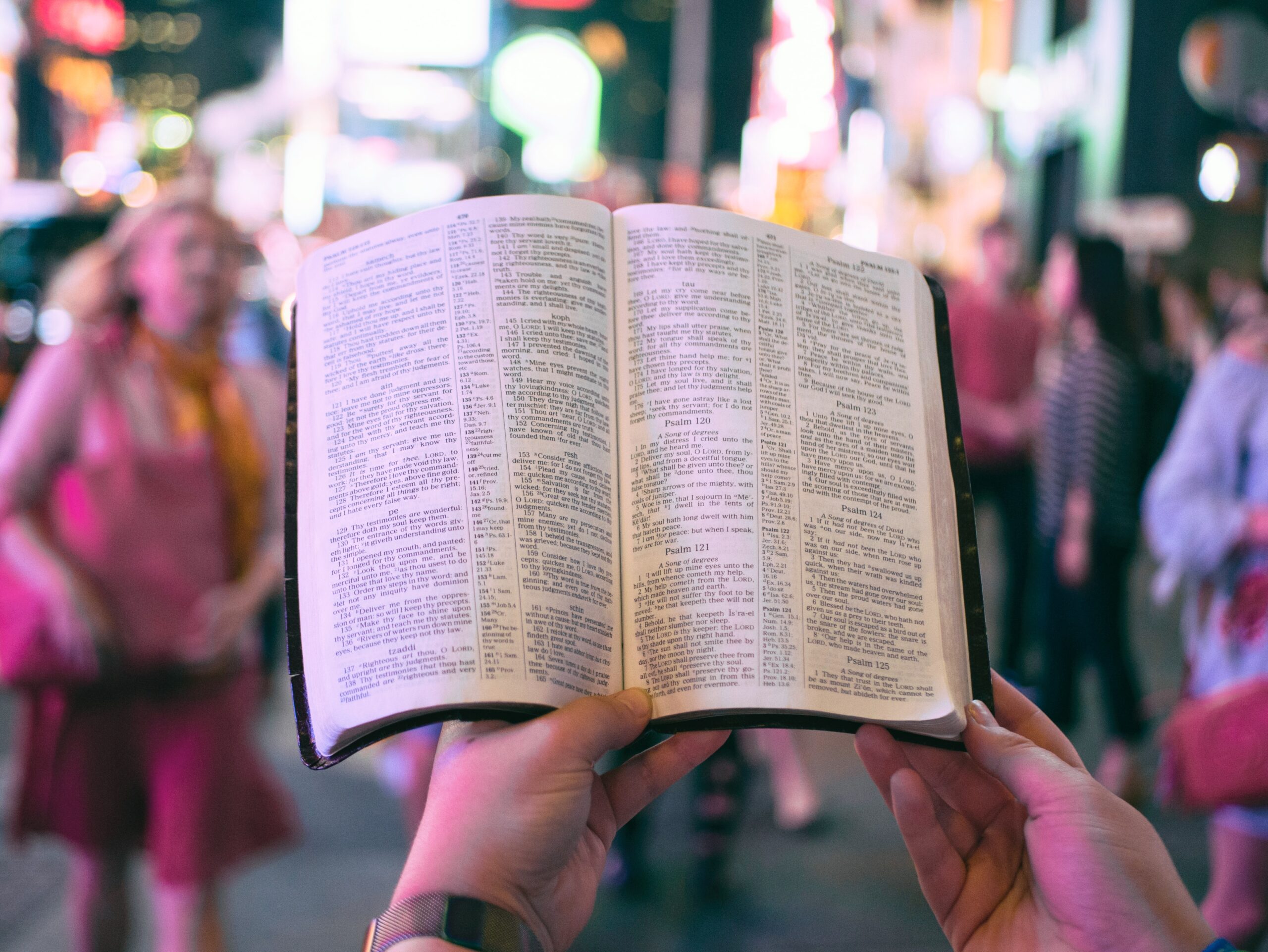 Book held infront of person in a busy city