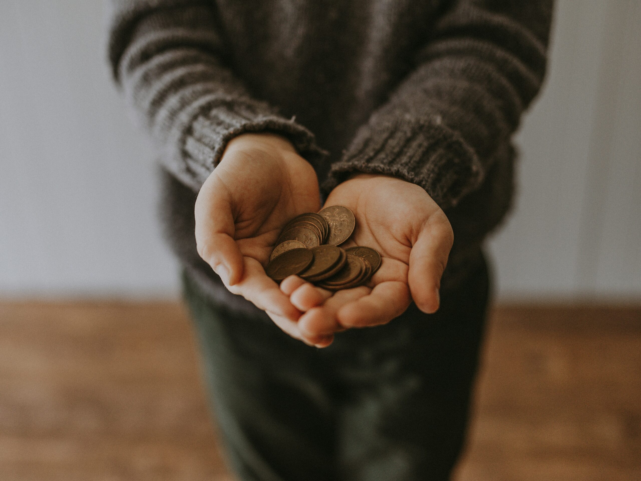 Child with hands out in front of them with coins in their hands