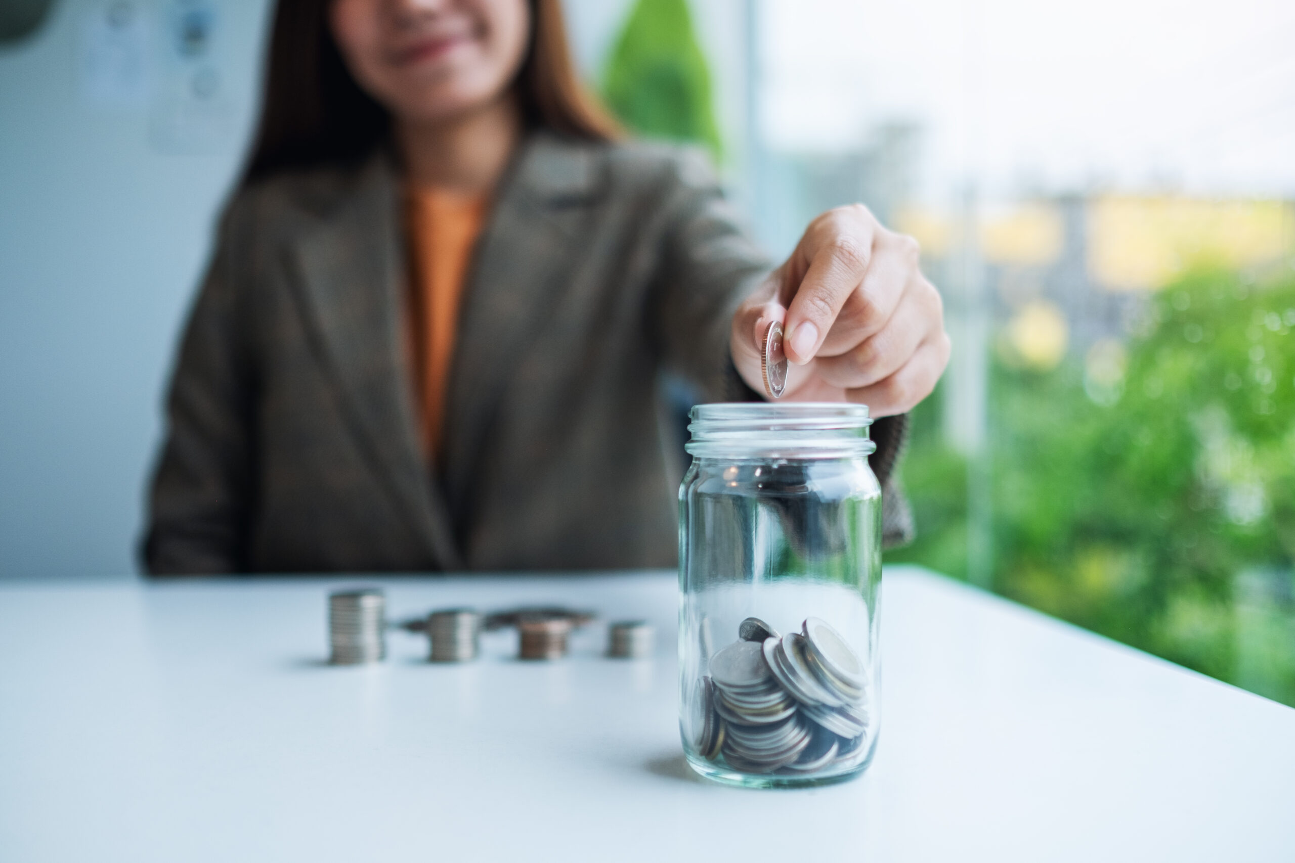Woman putting coins in a savings jar